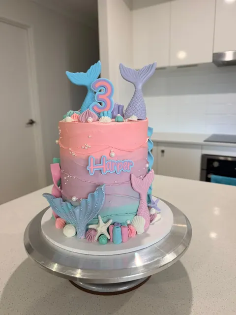 Tall pink, lilac and aqua mermaid cake with mermaid tails, shells and pearls for a third birthday